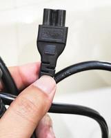 a man holding a 3 . plug laptop power cord photo