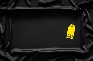 etiqueta de precio amarilla con palabra sobre fondo de tela negra. concepto de viernes negro. foto