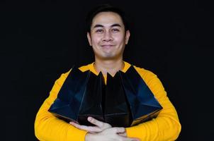 Asian male holding black shopping bags for Black Friday concept. photo