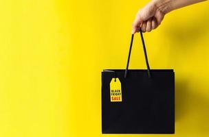 Hand holding shopping bag that have price tag with word for Black Friday shopping concept. photo