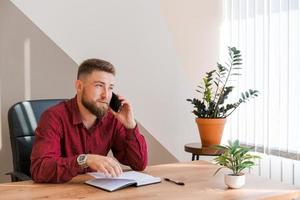 Business bearded man is talking on phone and plans to meet daily and write photo