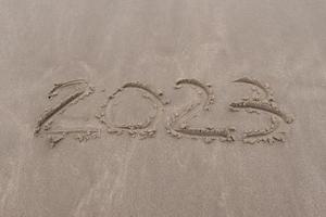 text 2023 on the sand of beach symbol new year 2023 photo