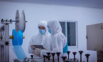 Technician worker wearing protective suite , glove are inspect ion with check  face mask manufacturing process to safe and against from virus. photo