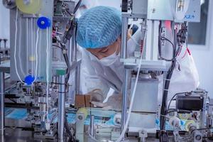 Technician worker wearing protective suite , glove are inspect ion with check  face mask manufacturing process to safe and against from virus. photo