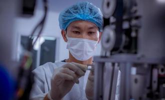 trabajador técnico que usa una suite protectora, los guantes se inspeccionan con el proceso de fabricación de máscaras faciales para asegurarse y evitar el virus. foto