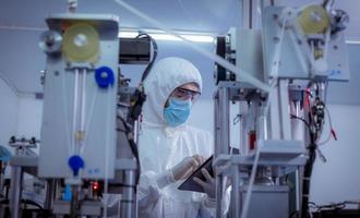 Technician worker wearing protective suite , glove are inspect ion with check  face mask manufacturing process to safe and against from virus. photo