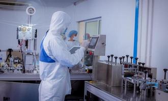 Technician worker wearing protective suite , glove are inspect ion with check  face mask manufacturing process to safe and against from virus. photo