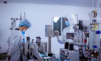 Technician worker wearing protective suite , glove are inspect ion with check  face mask manufacturing process to safe and against from virus. photo