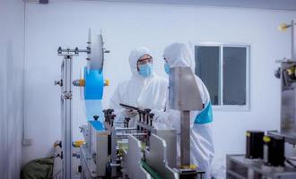 Technician worker wearing protective suite , glove are inspect ion with check  face mask manufacturing process to safe and against from virus. photo