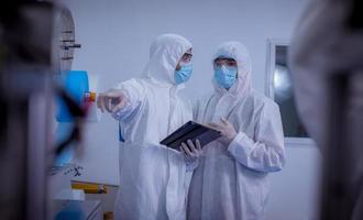 trabajador técnico que usa una suite protectora, los guantes se inspeccionan con el proceso de fabricación de máscaras faciales para asegurarse y evitar el virus. foto