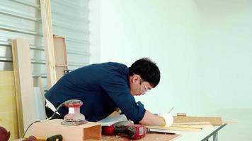 carpintero masculino midiendo y haciendo marcas de lápiz en tablones de madera. concepto de carpintería, artesanía y trabajo manual video