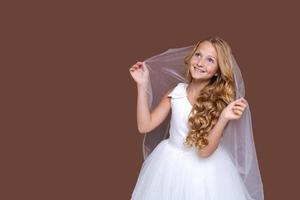 Beautiful cute girl in white dress with long wavy hair posing in studio photo