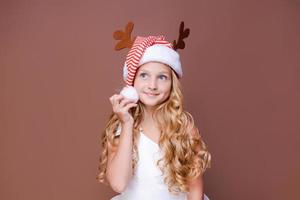 Beautiful girl in hat with deer antlers and in white dress smiles cutely photo