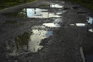 Large puddle on asphalt. Road with pits. Puddles on road. photo