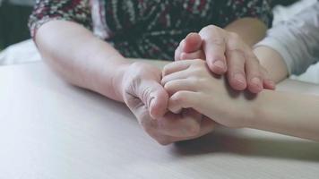close-up das mãos de trabalho de uma mulher adulta gentilmente segurando e acariciando as mãos de uma criança pequena. avó cuida de seu neto, acariciando suas mãos video
