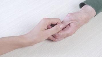 detailopname van een ouder Mens Holding de hand. een jong meisje duurt zorg van haar opa's Gezondheid. video