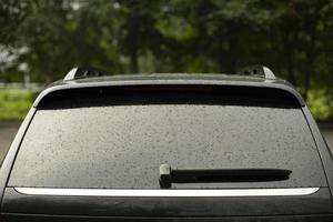 Wet car glass on back. Drops by car. Black vehicles in parking lot. photo