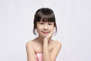 Asian young girl bright face and put his hand to his face on white background, Skin care beauty treatments concept. White model with clean, health skin of face. Children's products photo