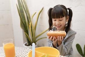 Beautiful young girl eating breakfast and orange juice on the holiday home table. healthy eating, food and snacks, Ham and Cheese Sandwich, eat and be happy photo