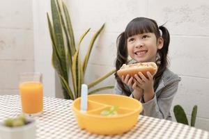 Beautiful young girl eating breakfast and orange juice on the holiday home table. healthy eating, food and snacks, Ham and Cheese Sandwich, eat and be happy photo