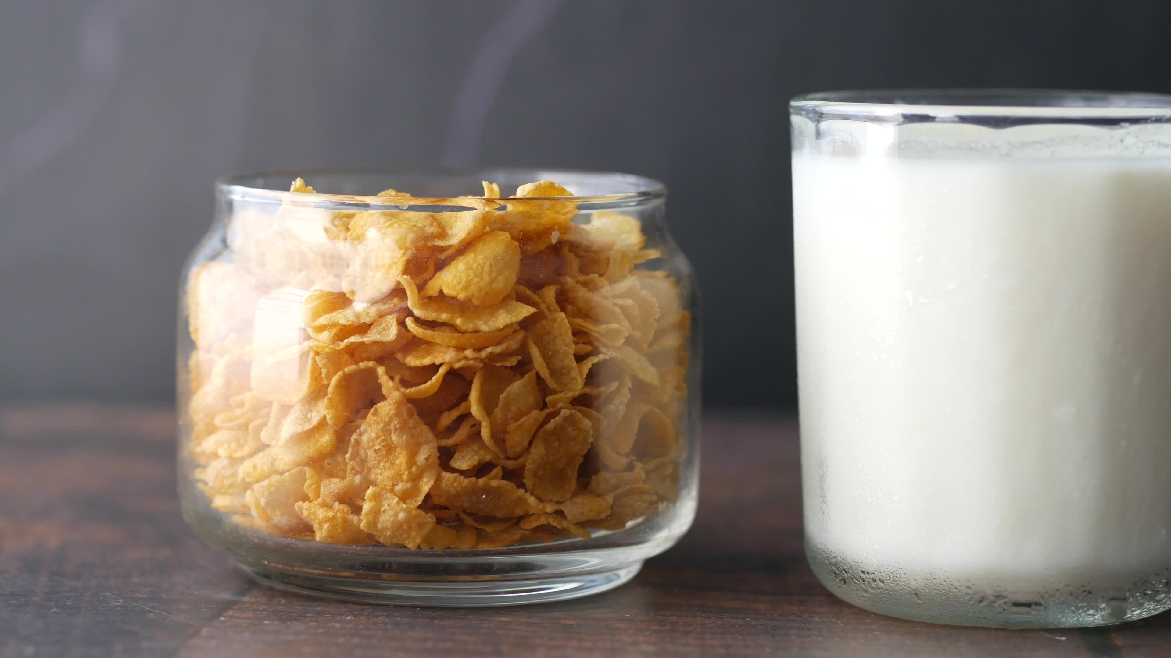 Corn flake cereal and milk in separate containers on table 13124758
