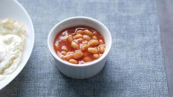 Baked beans fried eggs and toast on a table panning view video