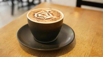 Tasse Latte mit Schaum und Nieselregen sitzt auf einer Untertasse am Cafétisch video