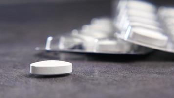 Close up of white pill on table near pill pack