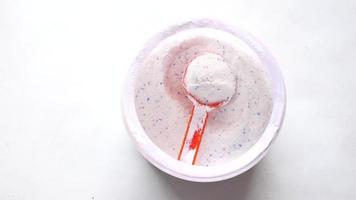 Overhead view of a white powder with red and blue specks and a red scoop video