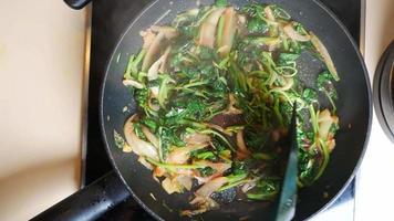 légumes verts et oignons sautés sur une cuisinière chaude video