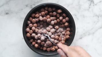 Hand stirs a spoon in a bowl of chocolate cereal and milk video