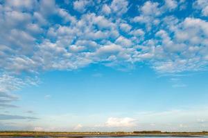 The vast sky is bright blue with many clouds moving. photo