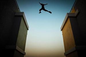 Concept of jumping over obstacles, The silhouette of a man jumping between two tall buildings. photo