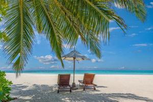hermosa isla tropical, dos sillas, sombrilla bajo hojas de palmera, cielo de arena de mar paraíso. paisaje de viajes de verano, playa de vacaciones escénica, naturaleza exótica idílica primer plano de recreación, relajación. foto