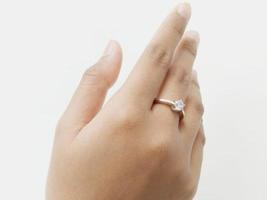 una joven de indonesia con un anillo de bodas en el dedo medio y sosteniendo un tallo de hoja en un fondo blanco foto