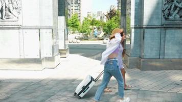 Two women with luggage outside talk and explore video