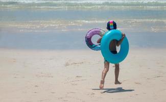 The boy with two swimming rings Running cheerfully on the beach photo