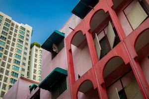 Old red pink building behind there is a large and tall modern condominium on a bright blue sky day. photo