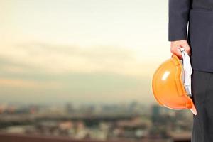 Engineers or architects are carrying a safety hat on the background of a tall building in the city. photo