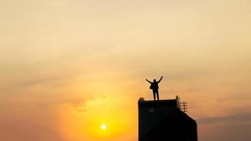 silueta de hombre en rofftop sobre cielo y fondo de luz solar, negocios, éxito, liderazgo, logro y concepto de personas foto