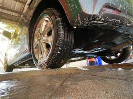 lavado de autos con vista de ángulo bajo con espuma para limpiar la suciedad y mantener la salud del conductor y los pasajeros. foto