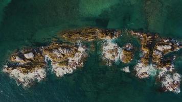 schöne vertikale luftaufnahme von blauen wellen, die über eine felsige küste an brechen video