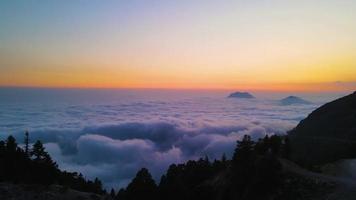 vista aérea das montanhas em nuvens laranja ao pôr do sol no verão. pico de montanha no nevoeiro. bela paisagem com rochas, colinas, céu. vista superior do drone. vale da montanha em nuvens baixas. vista de cima video