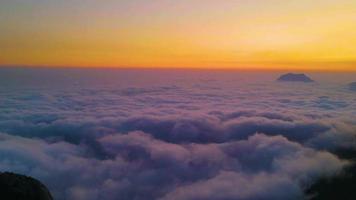 Aerial view of mountains in orange clouds at sunset in summer. Mountain peak in fog. Beautiful landscape with rocks, hills, sky. Top view from drone. Mountain valley in low clouds. View from above video