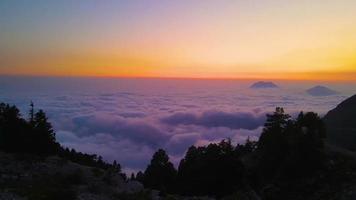 Aerial view of mountains in orange clouds at sunset in summer. Mountain peak in fog. Beautiful landscape with rocks, hills, sky. Top view from drone. Mountain valley in low clouds. View from above video