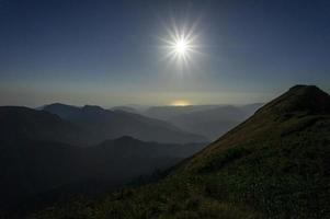 paisaje de montaña con siluetas de montañas y el sol poniente. hora dorada foto