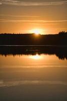 Sunset with reflection on a Swedish lake in Smalland. Romantic evening mood photo