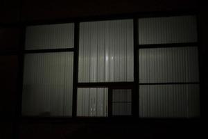 Big window at night. Window in building. Blinds cover light of lamp. photo