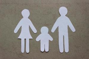 Silhouettes of family cutting from white paper on beige background. Mom, dad and son. Family with a child photo