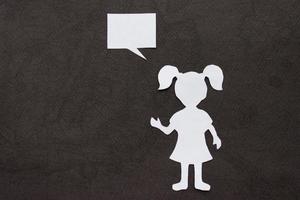 Silhouette of a girl in a dress and with ponytails made of white paper, cut by hand. In right side of the photo. With copy space. On black background photo